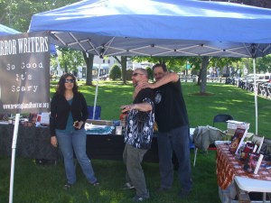 Author Scott Goudsward chokes author David Price after his latest book sale while author Tracy L. Carbone looks on. Photo by Jason Harris.