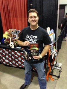 Author Gordon Bean holding his book, Dawn of Broken Glass, at the New England Horror Writers booth.