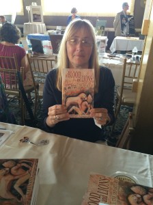 Author Karen Ann holding her book, Of Blood and Lions.